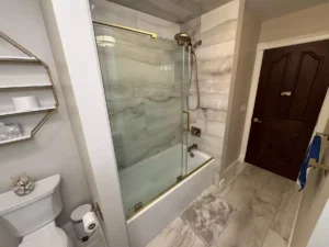 Glass-paned sliding shower door with gold accents.