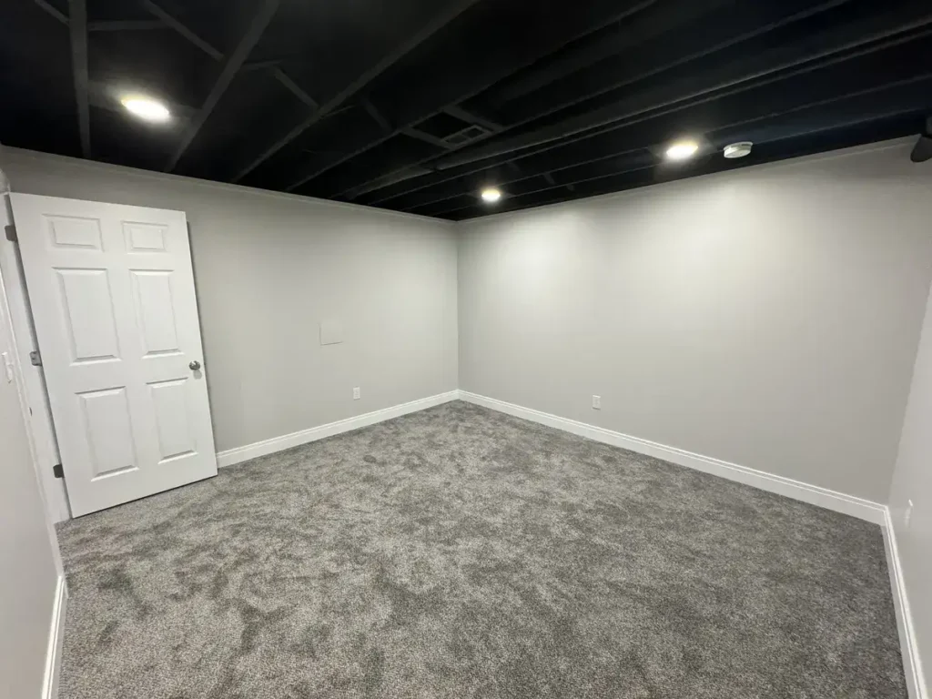 Full basement makeover featuring a spacious living area, an office, a bathroom, cozy carpet and trim for that at-home feel.