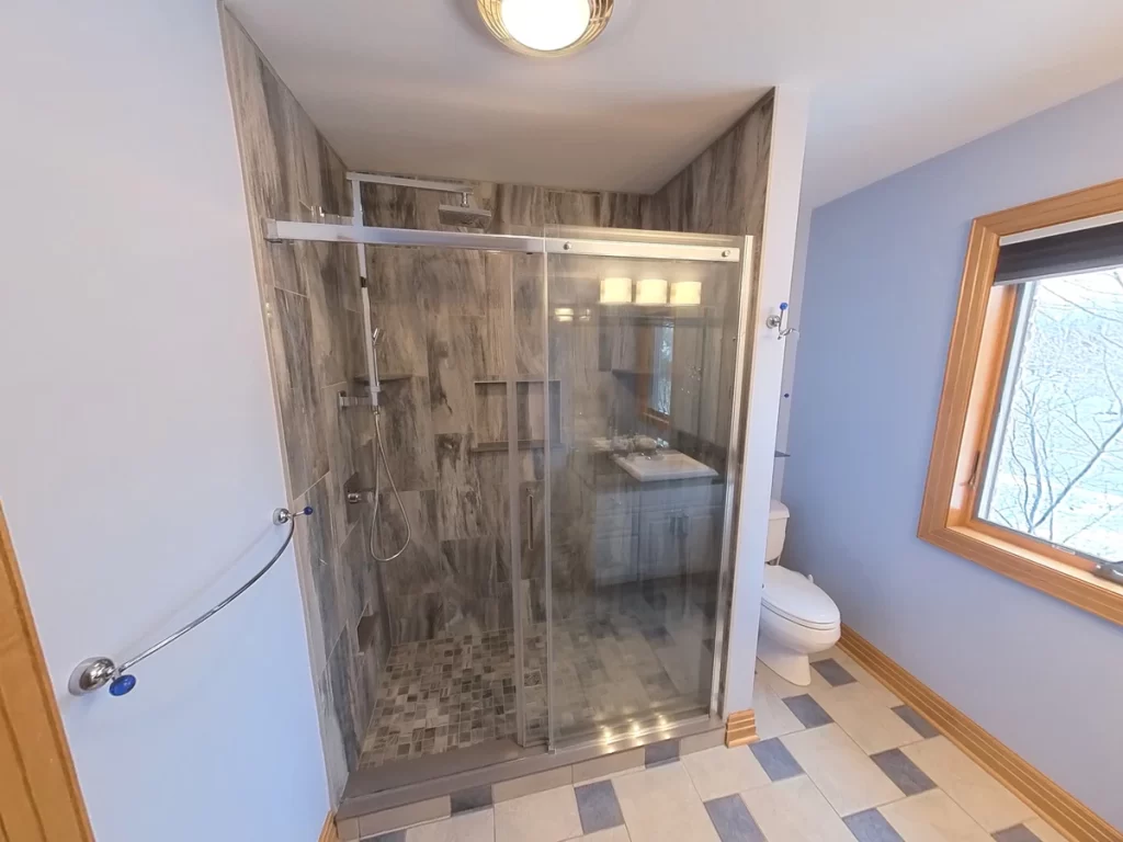View of a complete shower remodel featuring a transparent glass shower enclosure with gray marble-like tiles, showcasing Stately Kitchen and Bath's expertise in creating luxurious, functional shower spaces with detailed tile work and contemporary fixtures.