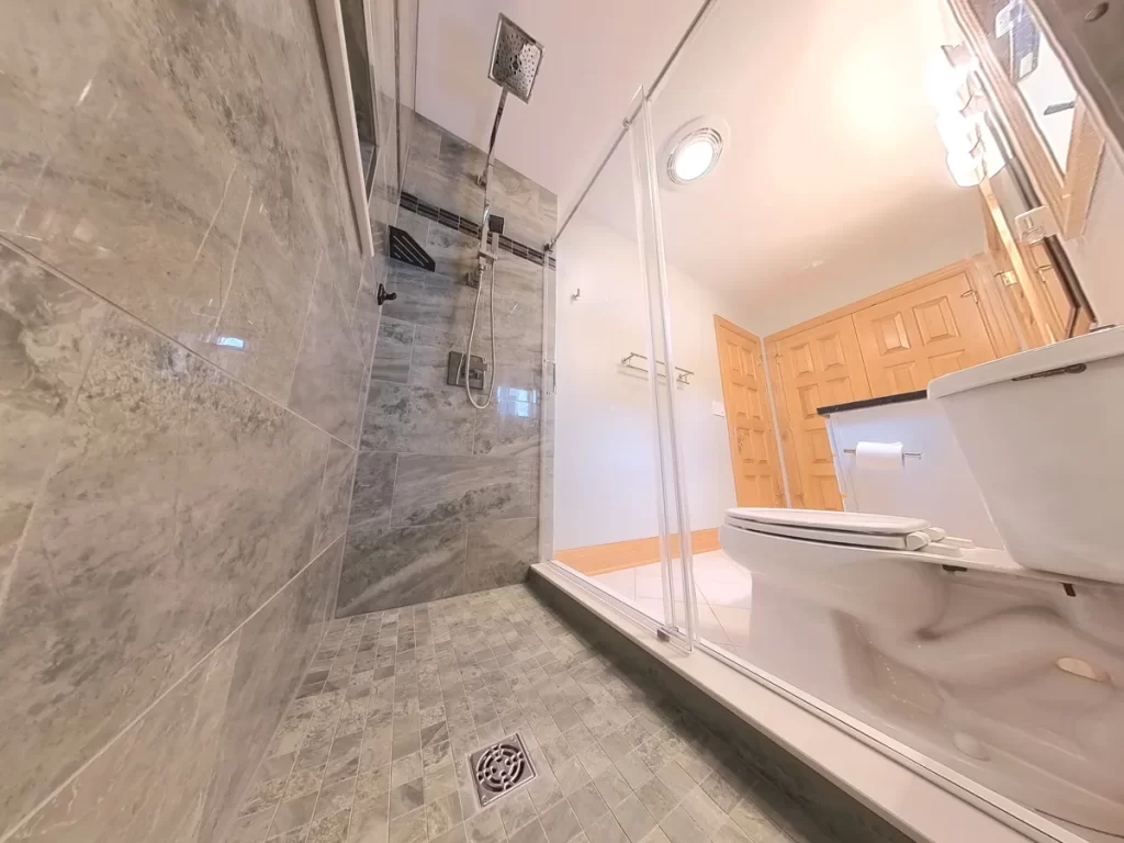 Elegant bathroom after renovation by Stately Kitchen and Bath featuring a sleek glass shower enclosure, upgraded fixtures, and sophisticated tile work