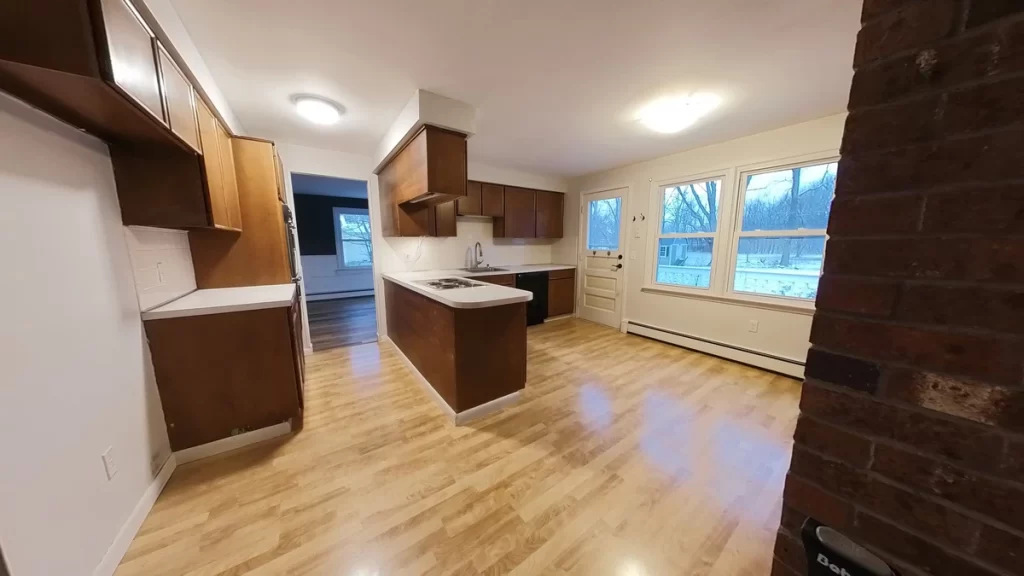 Before photo of a kitchen, prior to being remodeled, in Clarence, NY showing dated brown cabinets and cramped layout prior to Stately Builders renovation.