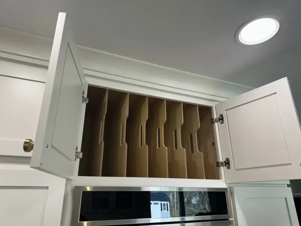 Custom-built white kitchen cabinet with vertical storage compartments for cutting boards in a Stately renovated kitchen in Clarence, NY.