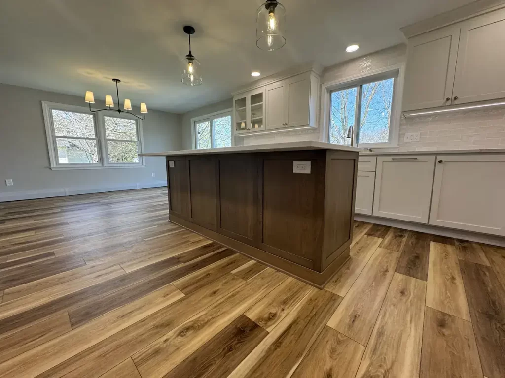 Newly renovated kitchen in Clarence, NY with contrasting island, elegant pendant lights, white cabinetry, and rich hardwood floors installed by Stately Kitchen & Bath.