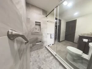 View from the shower area in a remodeled bathroom by Stately Kitchen and Bath in Gettzville, NY, featuring marble tile, built-in shelving, and modern fixtures.