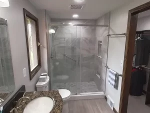 Close-up view of a bathroom remodel by Stately Kitchen and Bath in Gettzville, NY, showcasing a glass-enclosed shower with built-in shelving and modern fixtures.