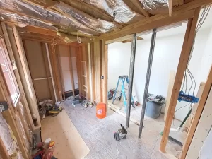 Bathroom under construction before remodel by Stately Kitchen and Bath in Gettzville, NY, showing exposed framing, insulation, and construction tools.