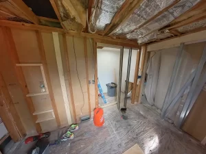 Exposed framing and insulation in a bathroom before remodel by Stately Kitchen and Bath in Gettzville, NY, with construction materials and tools visible.