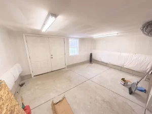 Clarence, NY home addition by Stately General Contracting, showcasing the newly expanded basement with ample storage space and double door access.