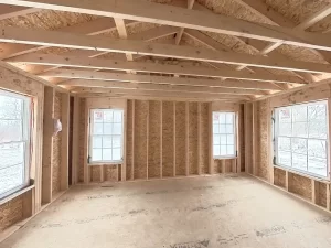 Stately General Contracting primary bedroom addition in Clarence, NY, during construction phase with framed walls and roof structure.