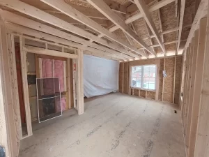 Construction progress of primary bedroom addition in Clarence, NY by Stately General Contracting, showing detailed framing and natural light through windows.