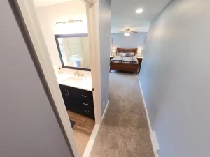 Stately General Contracting primary bedroom suite addition in Clarence, NY, showing the view from the hallway into the new bathroom and bedroom.