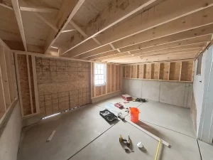 Framed basement extension under construction with exposed beams and tools.