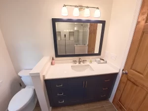 Stately General Contracting bathroom addition in Clarence, NY, showcasing a modern vanity with large mirror and adjacent toilet.