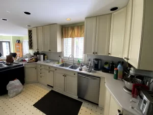 Kitchen sink area with white cabinets and a medium-sized window in Buffalo, NY before remodeling.