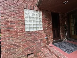Updated exterior, matched masonry work as part of entry expansion, with glass block window in Amherst, NY after remodeling by Stately Kitchen and Bath.