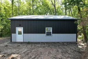 Side and rear view of a sturdy black and gray pole barn in Clarence, NY, highlighting the weather-resistant construction and versatile space.