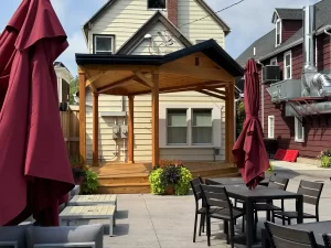 Wide shot of beer garden with soundstage at Buffalo Olde Brewing, showcasing comfortable seating and a wooden stage for live events.