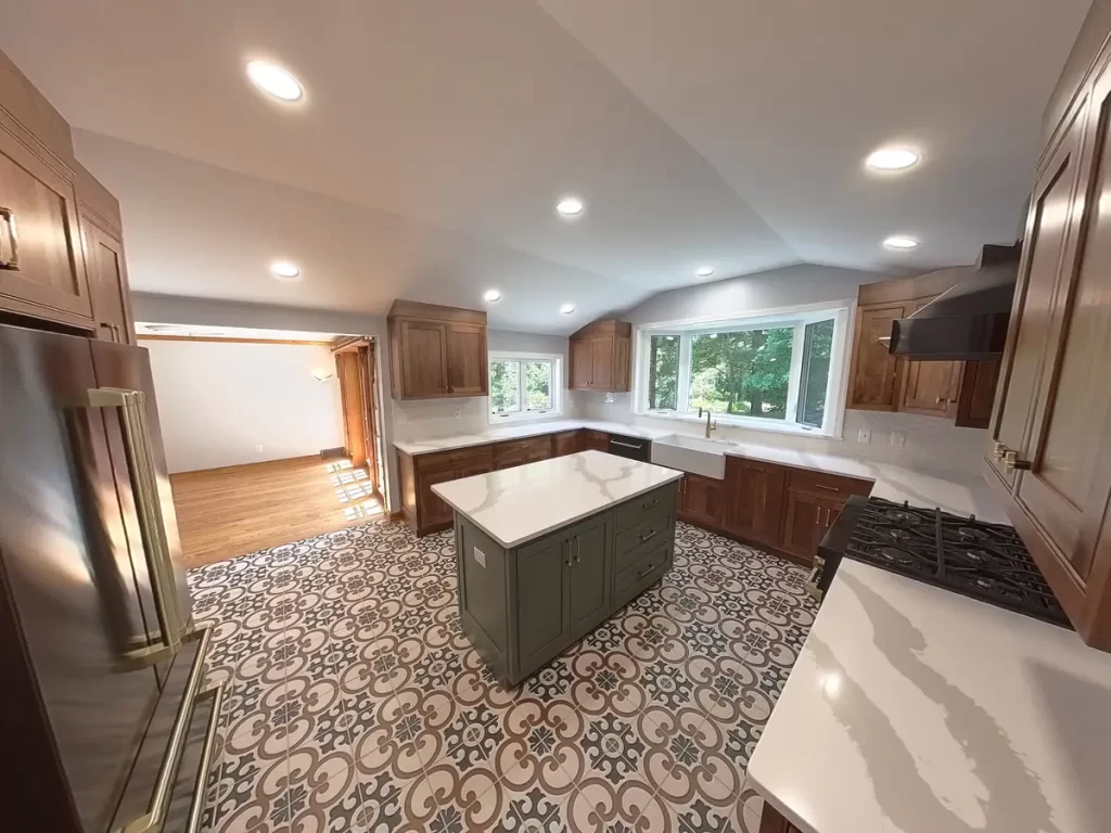 After remodel image of Elma, NY, kitchen featuring large windows, custom wooden cabinetry, patterned tile flooring, and a center island.