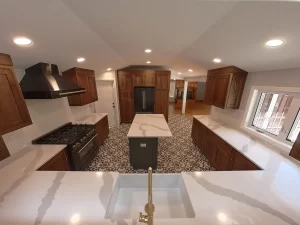 Remodeled kitchen in Elma, NY, showcasing a matte black stove with brass knobs, set against custom wood cabinetry and patterned flooring.