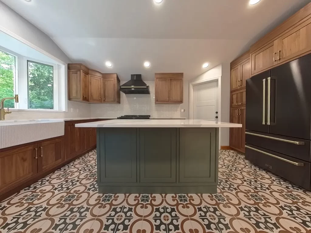 Wide view of remodeled kitchen in Elma, NY, showcasing a center island with white countertops, patterned tile flooring, and custom cabinetry.