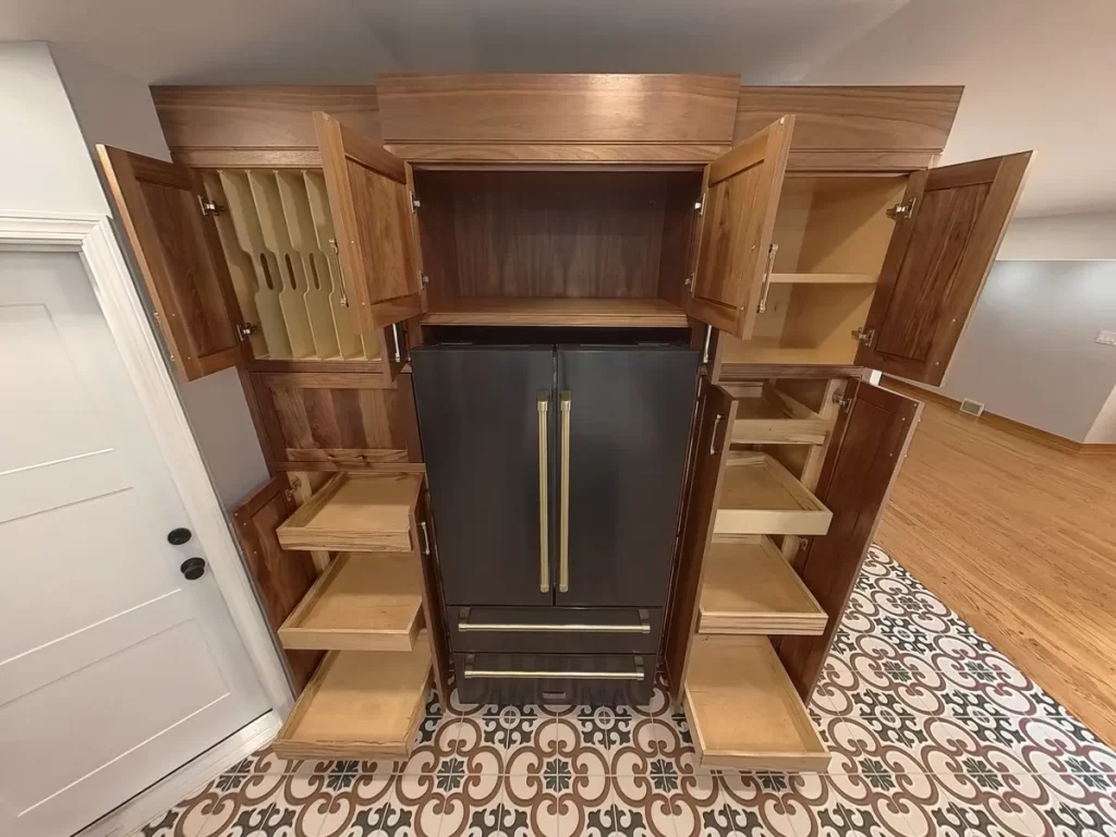 Remodeled kitchen in Elma, NY, featuring custom wooden cabinetry, black refrigerator with brass handles, and open shelves for storage solutions.