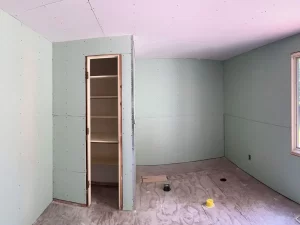 Bathroom build-out with installed drywall and a closet area, prepped for tile installation.