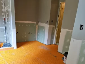 Bathroom under construction featuring radiant heated flooring underlayment, with partial drywall installation