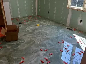 Partially installed floor tiles over radiant heating system, with tile spacers in place to ensure even installation.