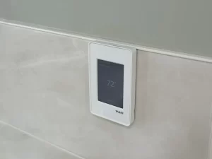 Close-up of a wall-mounted digital thermostat control for the radiant heated floors, mounted on the bathroom wall.