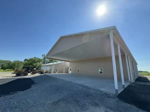 Wide view of the Bennington Highway Department pole barn construction, highlighting the finished metal roof and partially installed walls, as construction equipment and materials remain on-site.