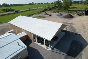 Overhead view of the completed Bennington Highway Department pole barn, displaying the roof and siding materials, along with the attached covered storage area, located in a rural setting.