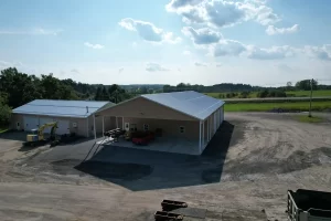 Stately_Post_Frame_Stately_Pole_Barn_Bennington_Highway_Department-17-Final Aerial view of the completed Bennington Highway Department pole barn, highlighting the large structure, parking area, and surrounding equipment storage space, set against a scenic backdrop.