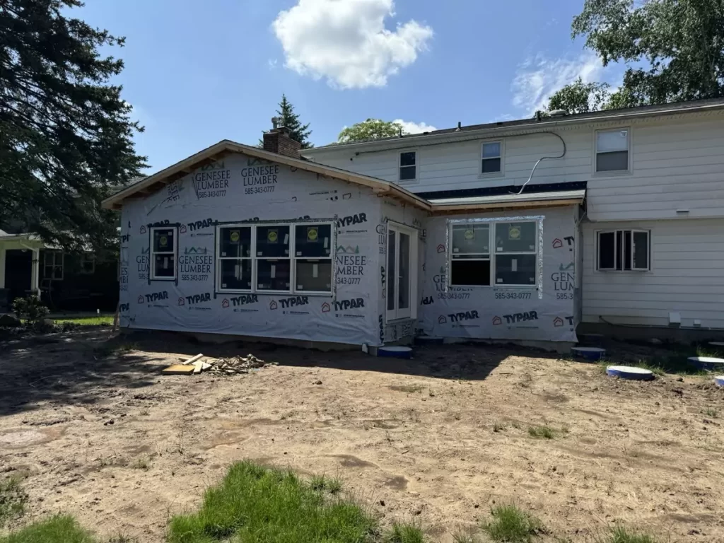 Home addition in Amherst, NY by Stately, showing framed exterior with Genesee Lumber wrap and new windows installed.