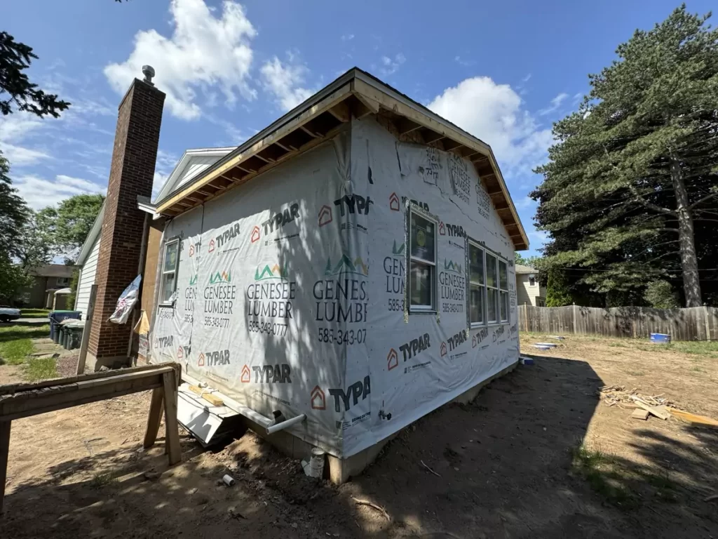 Angled view of exterior framing on a Stately home addition project in Amherst, NY, showcasing Genesee Lumber wrap and structural progress.