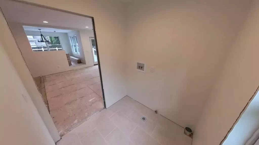 Laundry room addition in Amherst, NY by Stately, featuring floor tiling and connections for laundry equipment.
