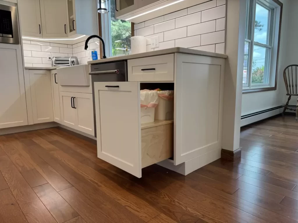 Pull-out trash compartment within kitchen cabinetry, designed for convenience and a seamless look.