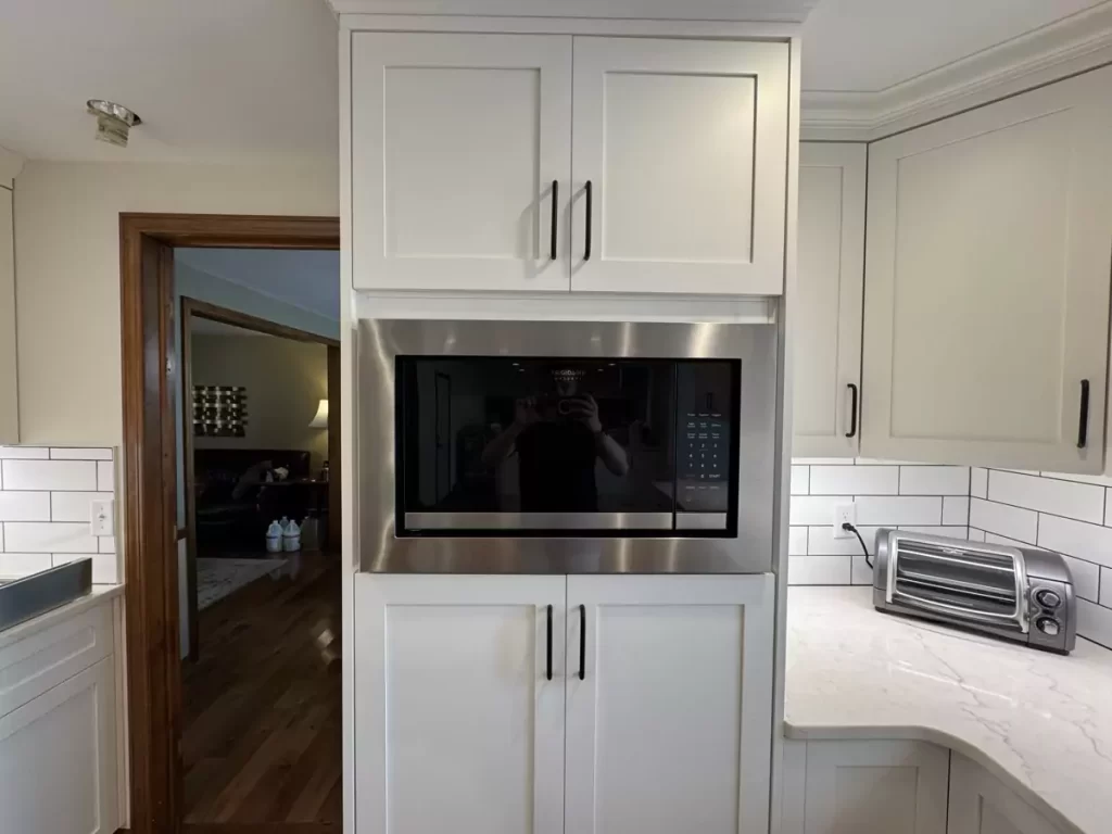 Close-up of built-in microwave within white kitchen cabinetry, showcasing functional and stylish appliance integration.