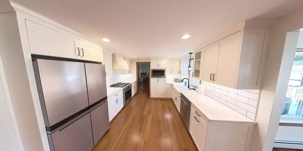 Spacious galley kitchen with stainless steel appliances, white cabinetry, and subway tile backsplash, showcasing modern elegance.