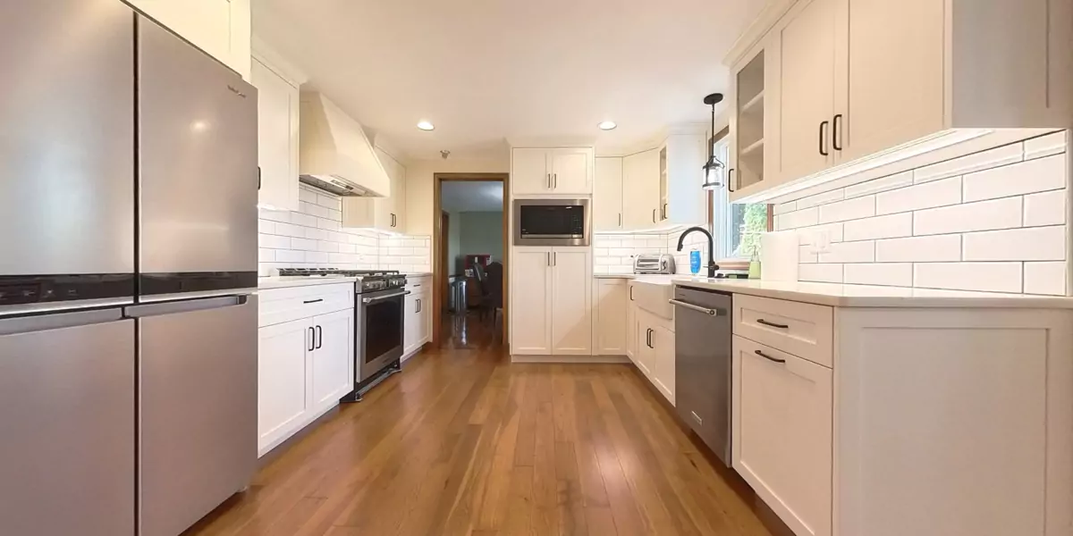 Spacious kitchen with ample natural light, featuring hardwood floors and white cabinets.