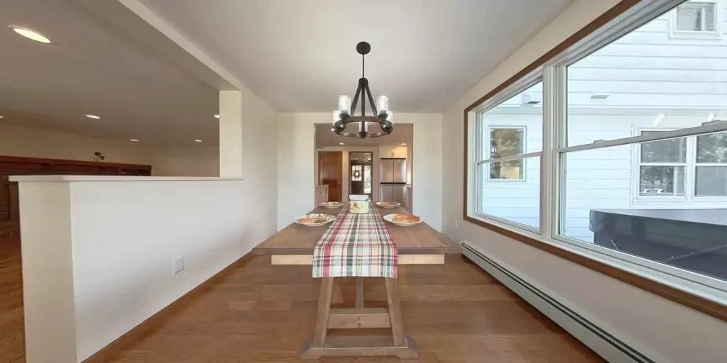 Dining area with natural light, wooden table, and chandelier in a cozy kitchen setup.