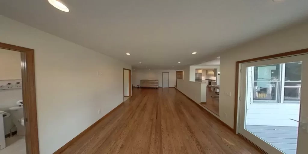 Spacious hardwood living area connecting bathroom, laundry, and kitchen areas in a modern open-concept home addition.