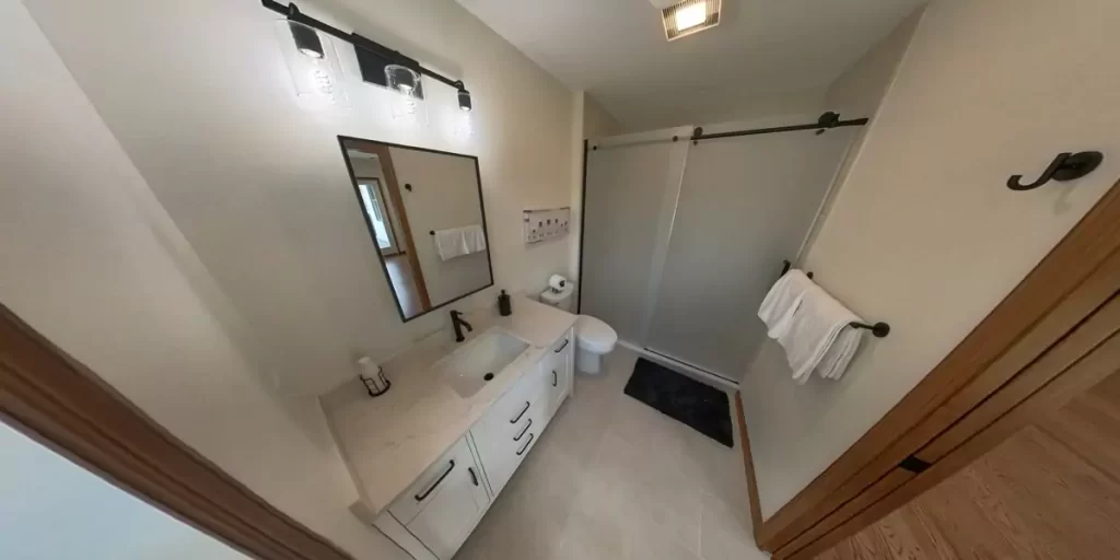 Bathroom vanity area with mirror, black faucet, and soft lighting in a modern beige-tiled bathroom.