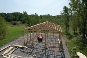 Stately Pole Barn framing in progress, with wooden trusses and framing beams being assembled at the construction site.