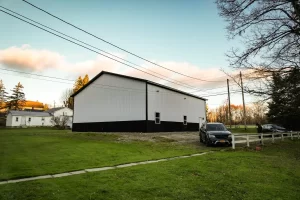 Wide-angle rear view of a Stately-built pole barn in a residential Holland, NY setting, blending durable construction with aesthetic appeal.