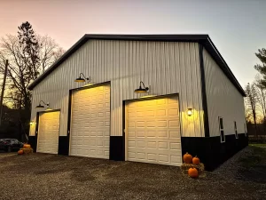 Twilight view of a Stately pole barn with glowing exterior lights, emphasizing high-quality construction and stylish design in Holland, NY.