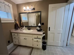 Outdated bathroom with basic vanity and plain tile flooring before remodeling in Clarence, NY.