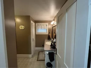 Outdated bathroom with basic vanity and plain tile flooring before remodeling in Clarence, NY