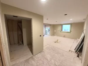 Construction progress showing finished drywall, entry to new bathroom, and open-concept kitchen.