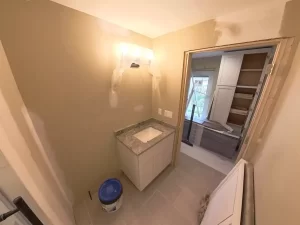 Bathroom renovation featuring a compact vanity with granite countertop and soft lighting.