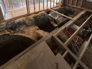 Kitchen demolition showing stripped walls, exposed ductwork, and open well in Clarence, NY.